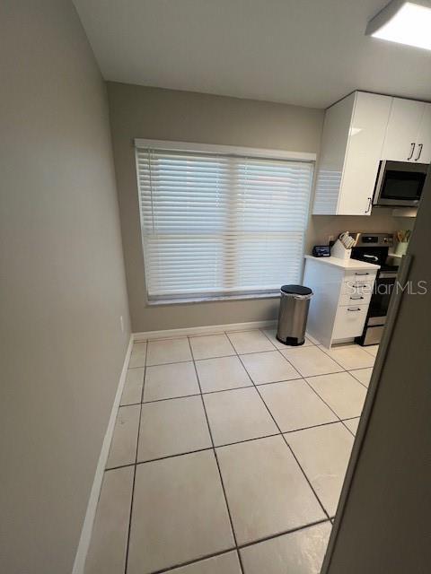 kitchen with white cabinetry, light tile patterned flooring, and stainless steel appliances