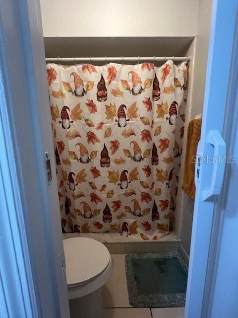 bathroom with a shower with curtain, tile patterned flooring, and toilet