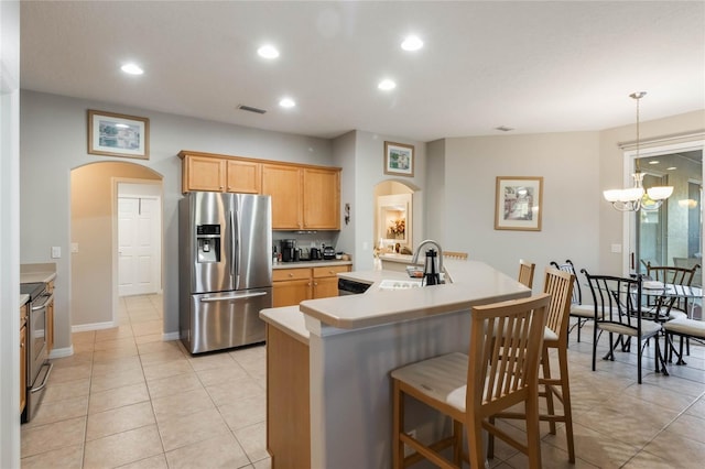 kitchen with sink, stainless steel appliances, a notable chandelier, a kitchen island with sink, and light tile patterned flooring