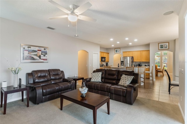 living room featuring ceiling fan, light tile patterned floors, and a textured ceiling