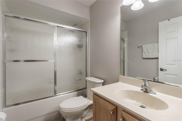 full bathroom with combined bath / shower with glass door, vanity, and toilet