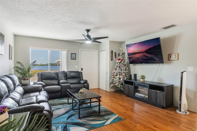 living room with ceiling fan, wood-type flooring, and a textured ceiling