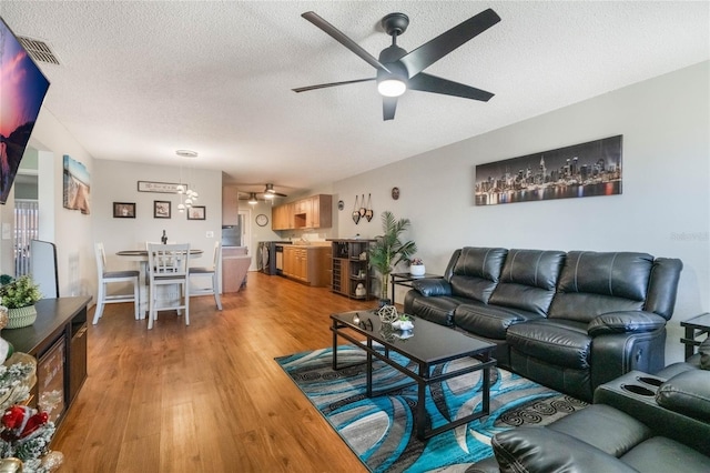 living room featuring hardwood / wood-style floors, ceiling fan, and a textured ceiling