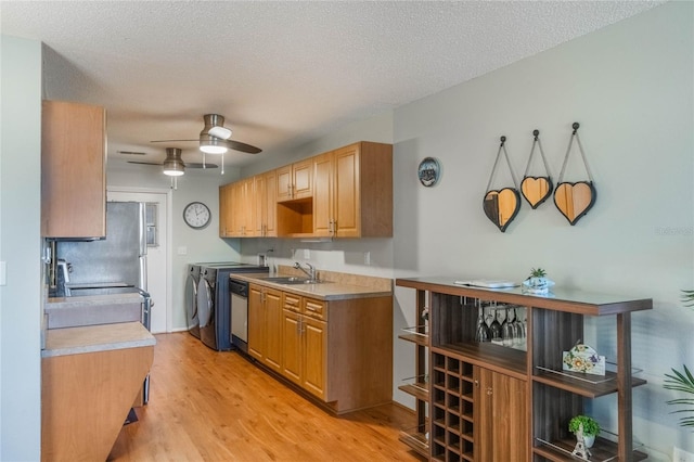 kitchen featuring a textured ceiling, ceiling fan, sink, light hardwood / wood-style flooring, and washing machine and dryer