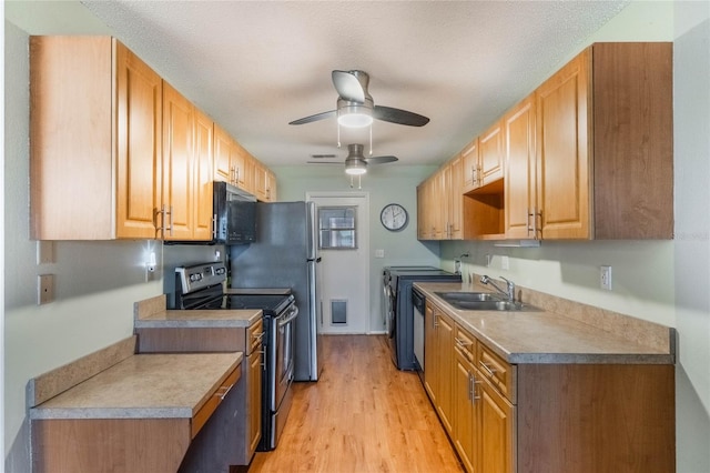 kitchen featuring appliances with stainless steel finishes, light wood-type flooring, a textured ceiling, ceiling fan, and sink