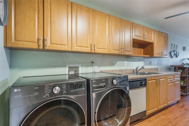 clothes washing area with separate washer and dryer, sink, and light hardwood / wood-style floors