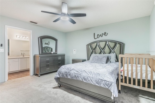 carpeted bedroom with connected bathroom, ceiling fan, and sink