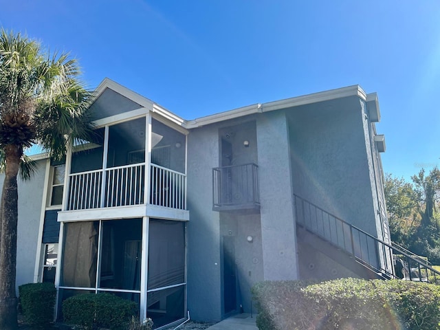 rear view of house featuring a sunroom and a balcony