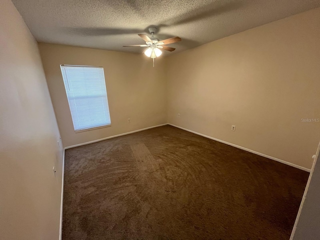 unfurnished room with ceiling fan, dark carpet, and a textured ceiling