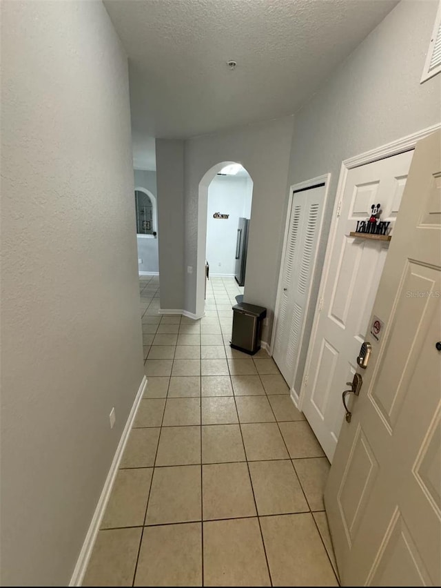 corridor with light tile patterned floors and a textured ceiling