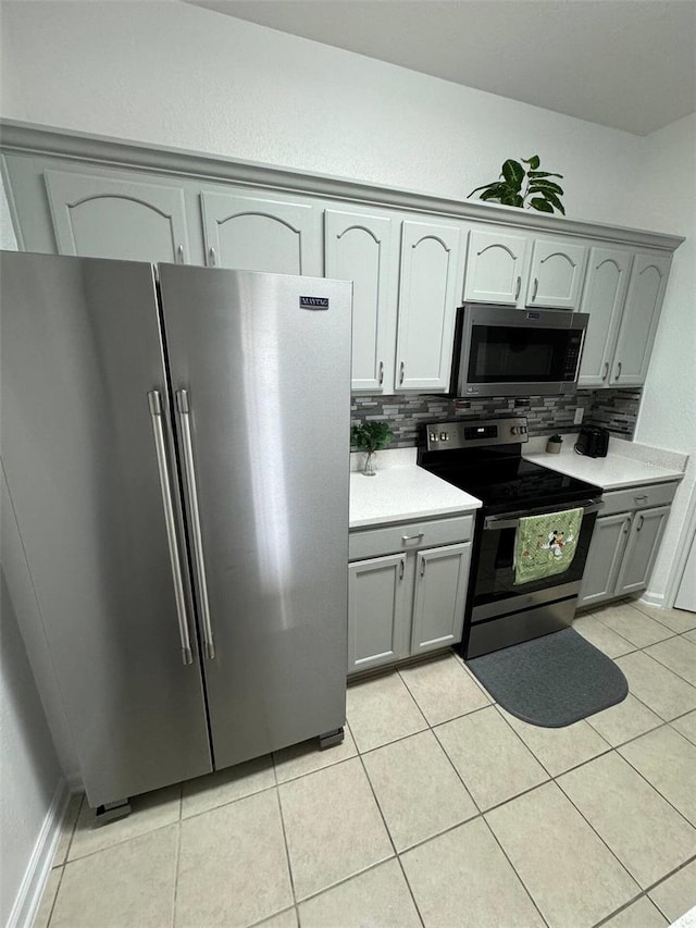 kitchen with tasteful backsplash, gray cabinets, light tile patterned floors, and stainless steel appliances