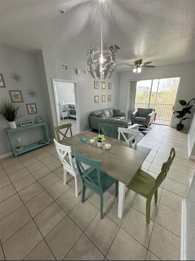 dining room with ceiling fan with notable chandelier, light tile patterned floors, and a textured ceiling