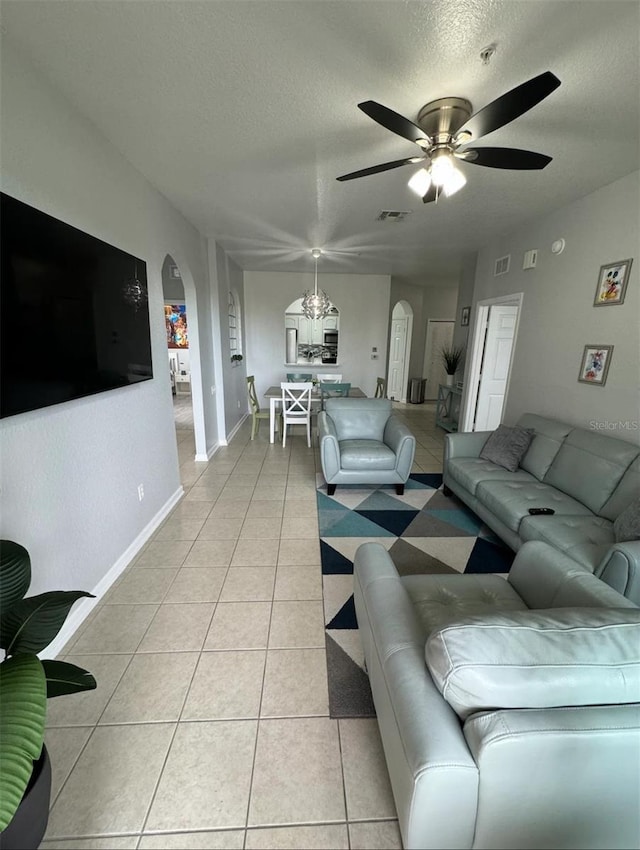 living room featuring light tile patterned floors, a textured ceiling, and ceiling fan