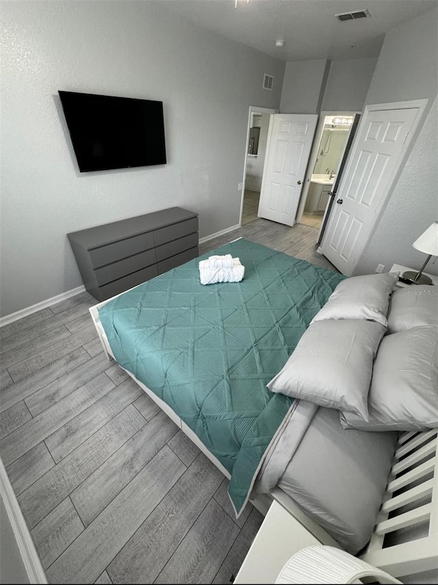 bedroom with hardwood / wood-style flooring and ensuite bathroom