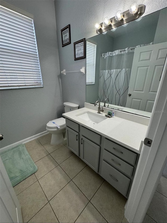 bathroom with toilet, vanity, and tile patterned floors