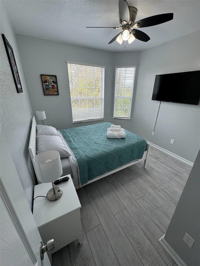 bedroom with ceiling fan, a textured ceiling, and hardwood / wood-style flooring