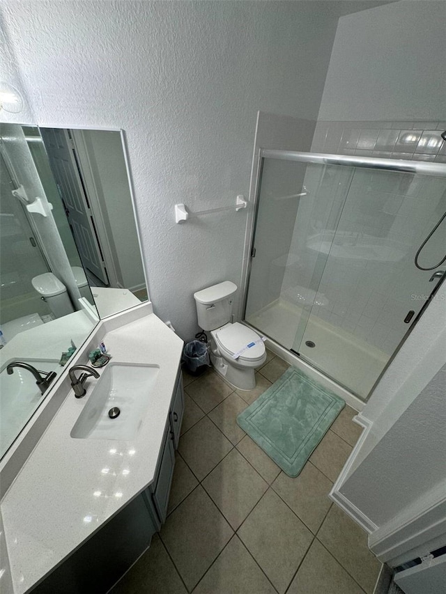 bathroom featuring tile patterned flooring, vanity, toilet, and an enclosed shower