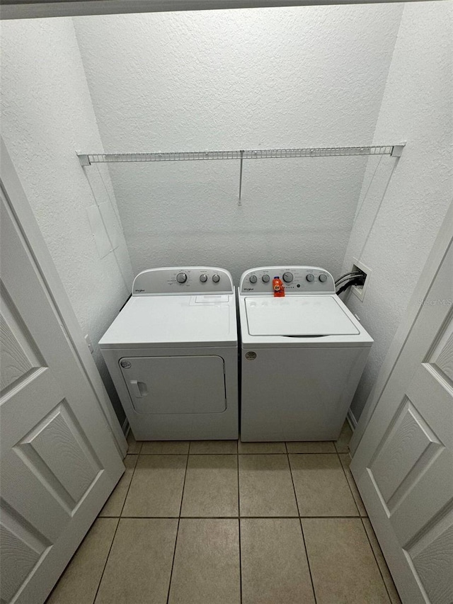 clothes washing area with light tile patterned flooring and washer and dryer