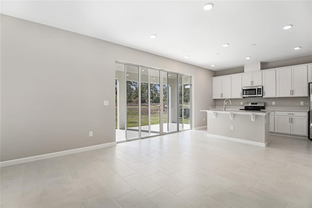 kitchen featuring appliances with stainless steel finishes, a breakfast bar, sink, white cabinetry, and an island with sink