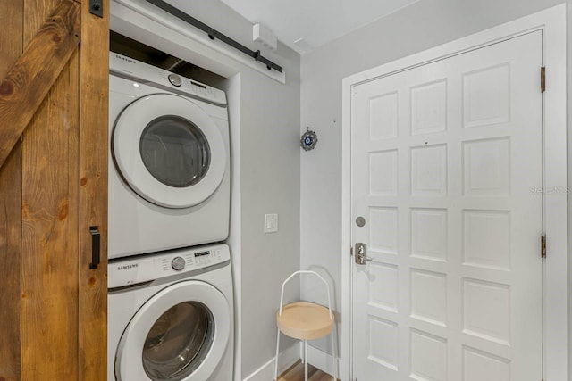 laundry room featuring a barn door and stacked washer / dryer