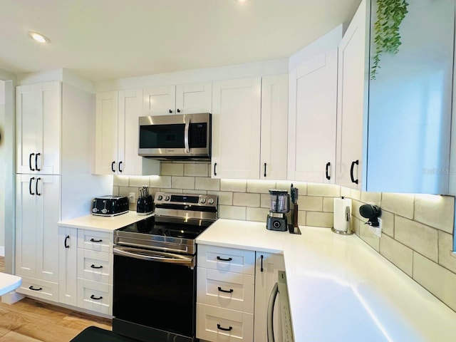 kitchen featuring decorative backsplash, white cabinets, stainless steel appliances, and light wood-type flooring