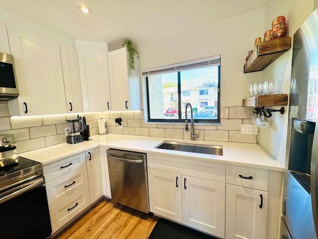 kitchen with white cabinets, stainless steel appliances, light hardwood / wood-style floors, and sink