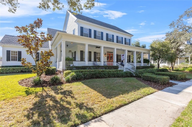 view of front of home with covered porch, ceiling fan, and a front yard