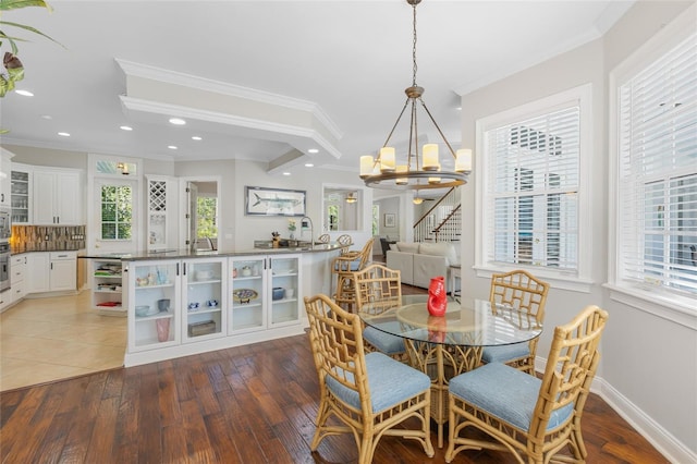 dining area with hardwood / wood-style floors, an inviting chandelier, and ornamental molding