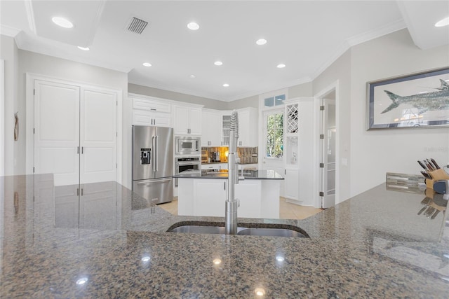 kitchen featuring dark stone counters, white cabinets, ornamental molding, and appliances with stainless steel finishes