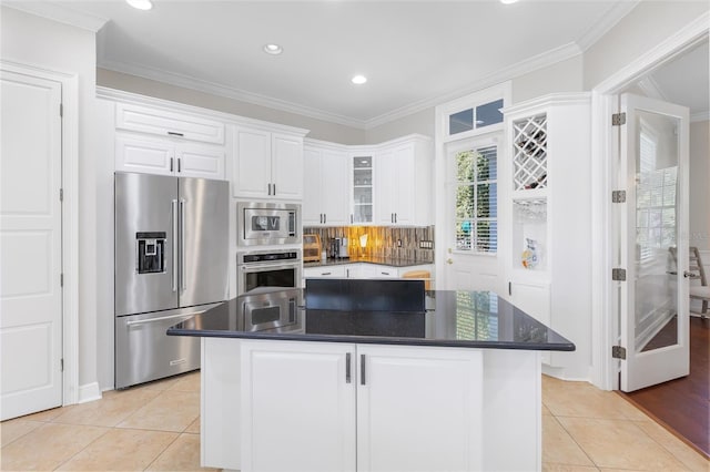 kitchen with white cabinets, appliances with stainless steel finishes, a kitchen island, and ornamental molding