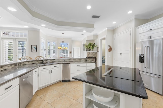 kitchen featuring appliances with stainless steel finishes, ornamental molding, sink, white cabinets, and a kitchen island