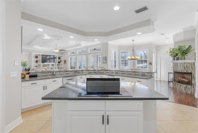 kitchen with kitchen peninsula, decorative light fixtures, light tile patterned flooring, ceiling fan with notable chandelier, and ornamental molding