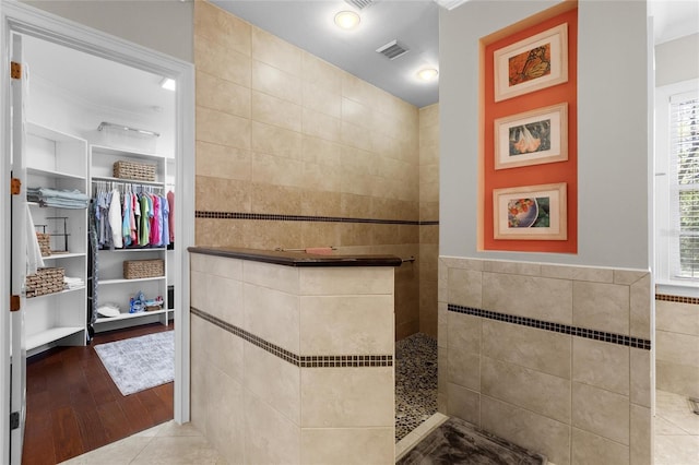 bathroom with wood-type flooring, tile walls, and walk in shower