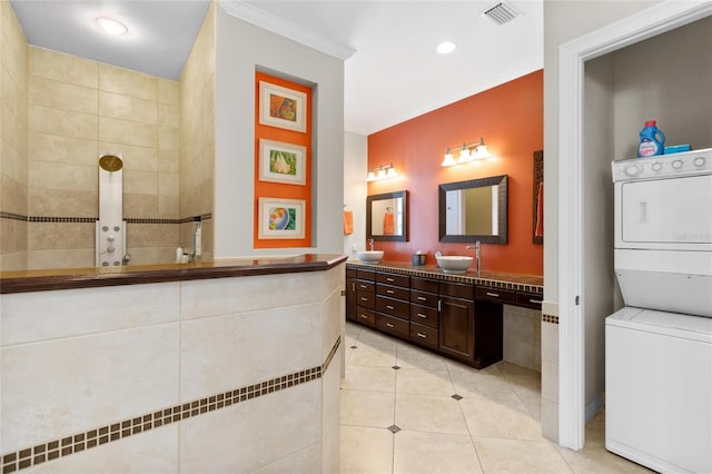 bathroom featuring tile patterned flooring, vanity, ornamental molding, and stacked washer and clothes dryer