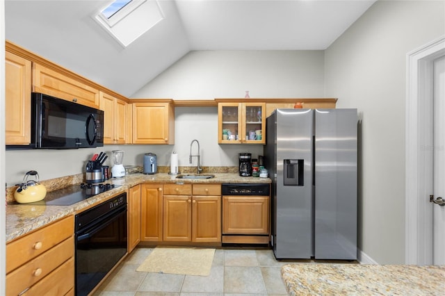 kitchen with light stone countertops, sink, lofted ceiling with skylight, light tile patterned flooring, and black appliances