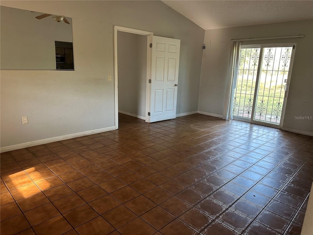 empty room with a textured ceiling, ceiling fan, dark tile patterned floors, and vaulted ceiling