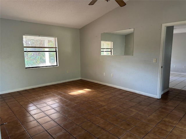 empty room with dark tile patterned flooring, ceiling fan, lofted ceiling, and a textured ceiling