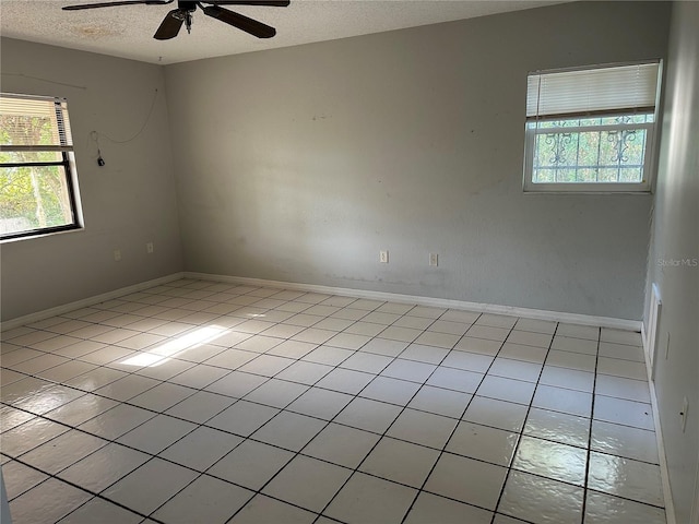 spare room with ceiling fan, light tile patterned floors, and a textured ceiling