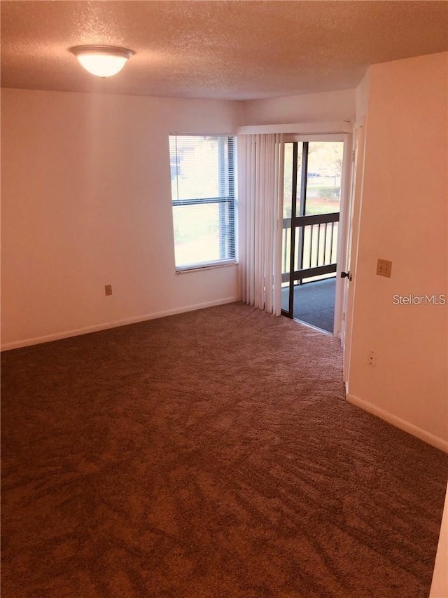 carpeted empty room featuring a textured ceiling