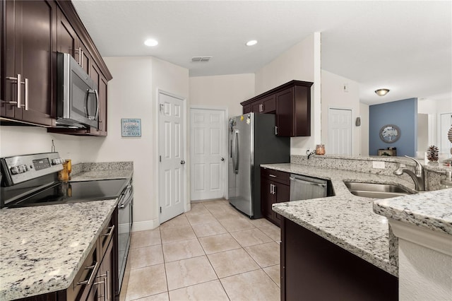 kitchen with light stone countertops, sink, kitchen peninsula, light tile patterned flooring, and appliances with stainless steel finishes