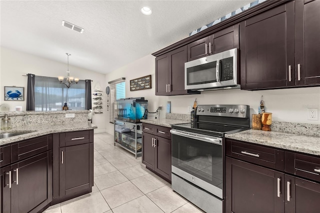 kitchen featuring appliances with stainless steel finishes, vaulted ceiling, sink, a chandelier, and hanging light fixtures