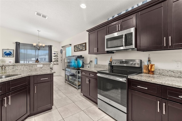 825 Desmoines Pl, Kissimmee, FL 34759 - kitchen featuring appliances with stainless steel finishes, a sink, lofted ceiling, a chandelier, and light tile patterned floors