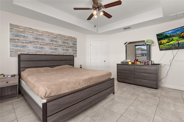 bedroom featuring light tile patterned floors, a tray ceiling, and ceiling fan