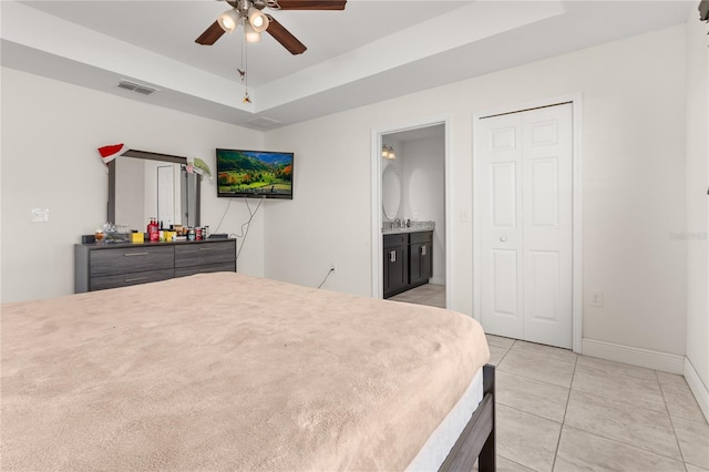 bedroom with a raised ceiling, ceiling fan, light tile patterned flooring, and ensuite bathroom