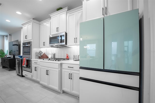 kitchen with white cabinets, light tile patterned floors, backsplash, and stainless steel appliances