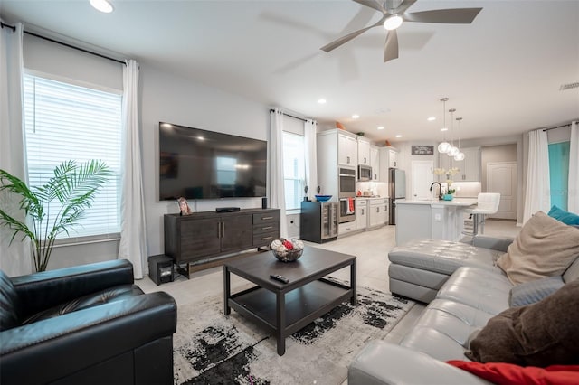 living room featuring ceiling fan, plenty of natural light, and sink