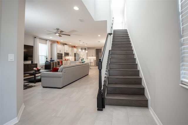 stairs featuring ceiling fan