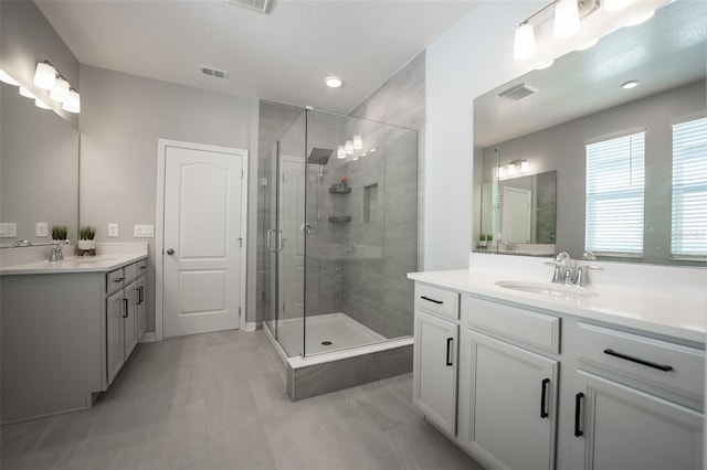 bathroom with tile patterned flooring, vanity, an enclosed shower, and a textured ceiling