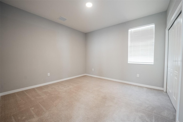 unfurnished bedroom with light colored carpet and a closet