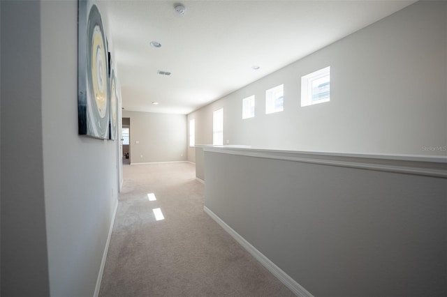 hall featuring light colored carpet and a healthy amount of sunlight